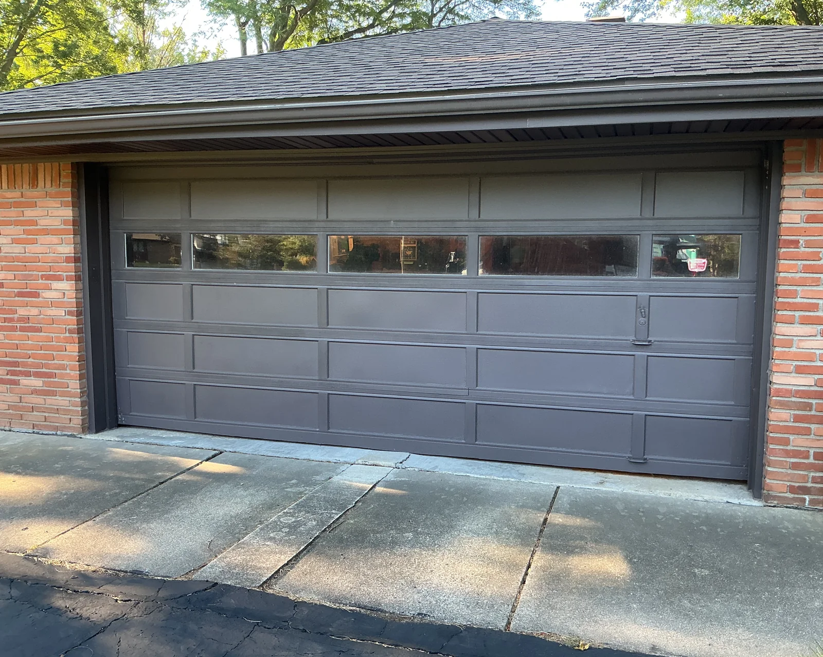 Original painted garage door with rectangular panels and a horizontal row of windows.