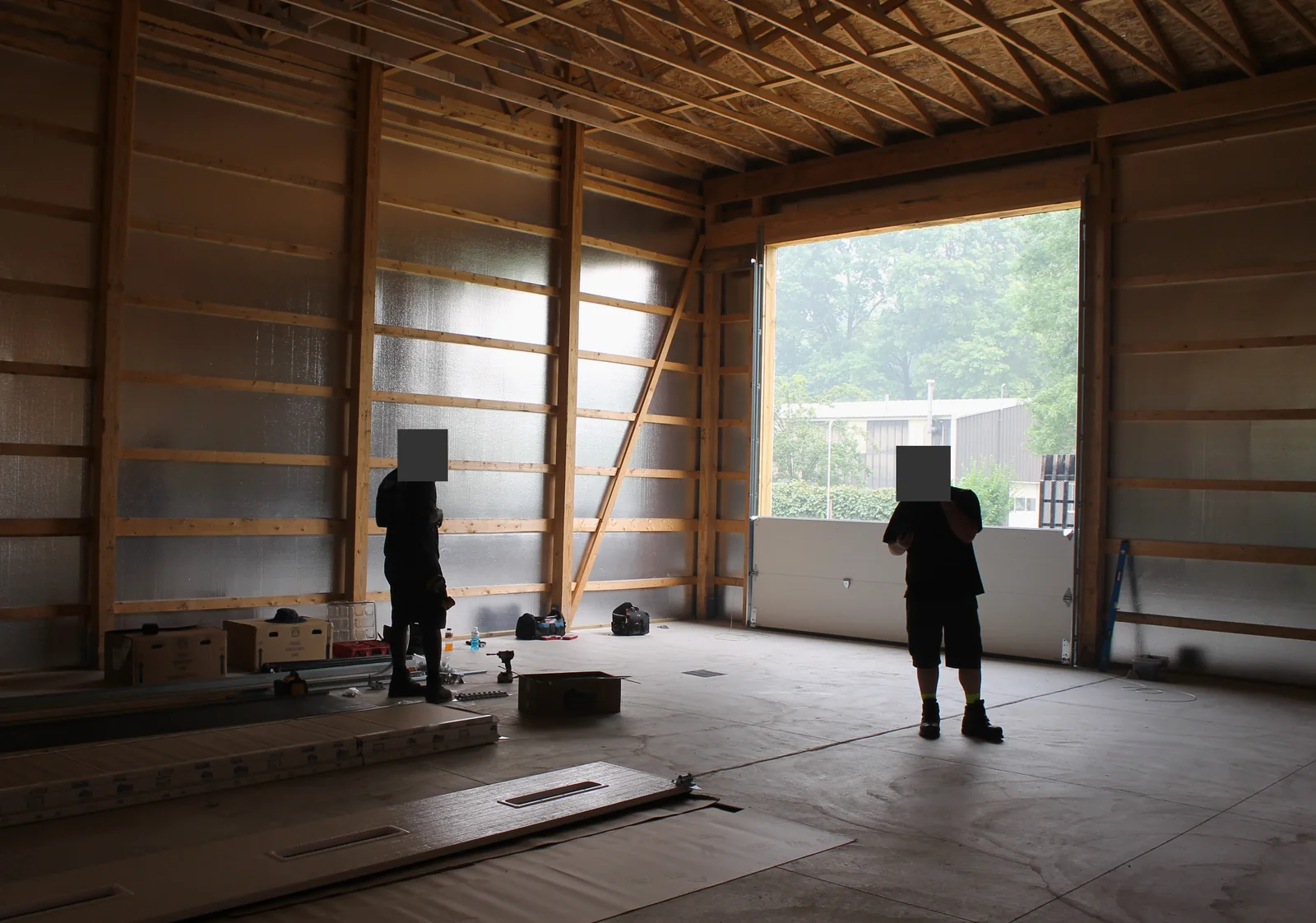 Installers working around a tall barn opening with a lower door section in place.