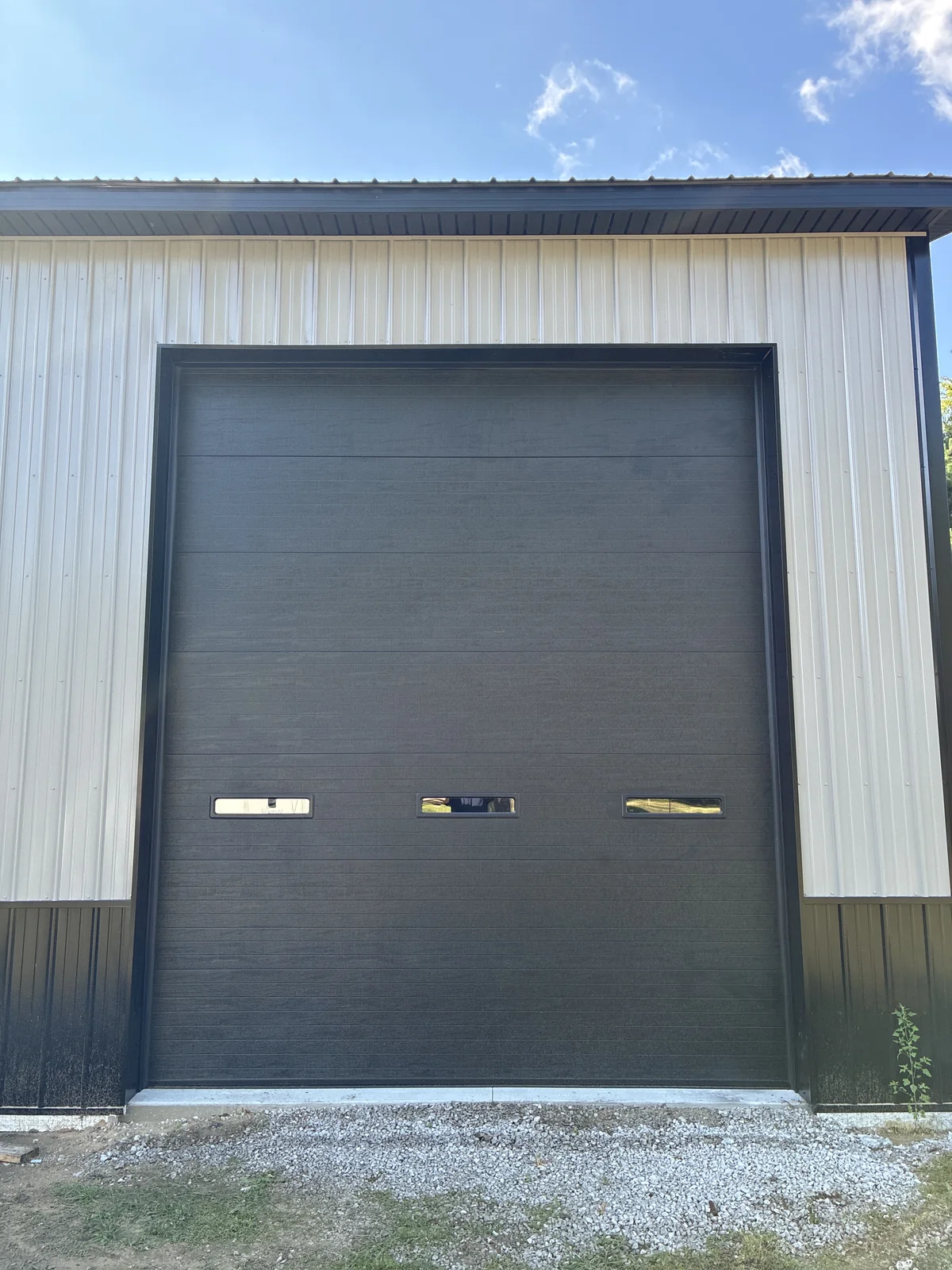 Tall Carbon Black overhead door with three narrow vision lites on a Flat Rock utility barn.
