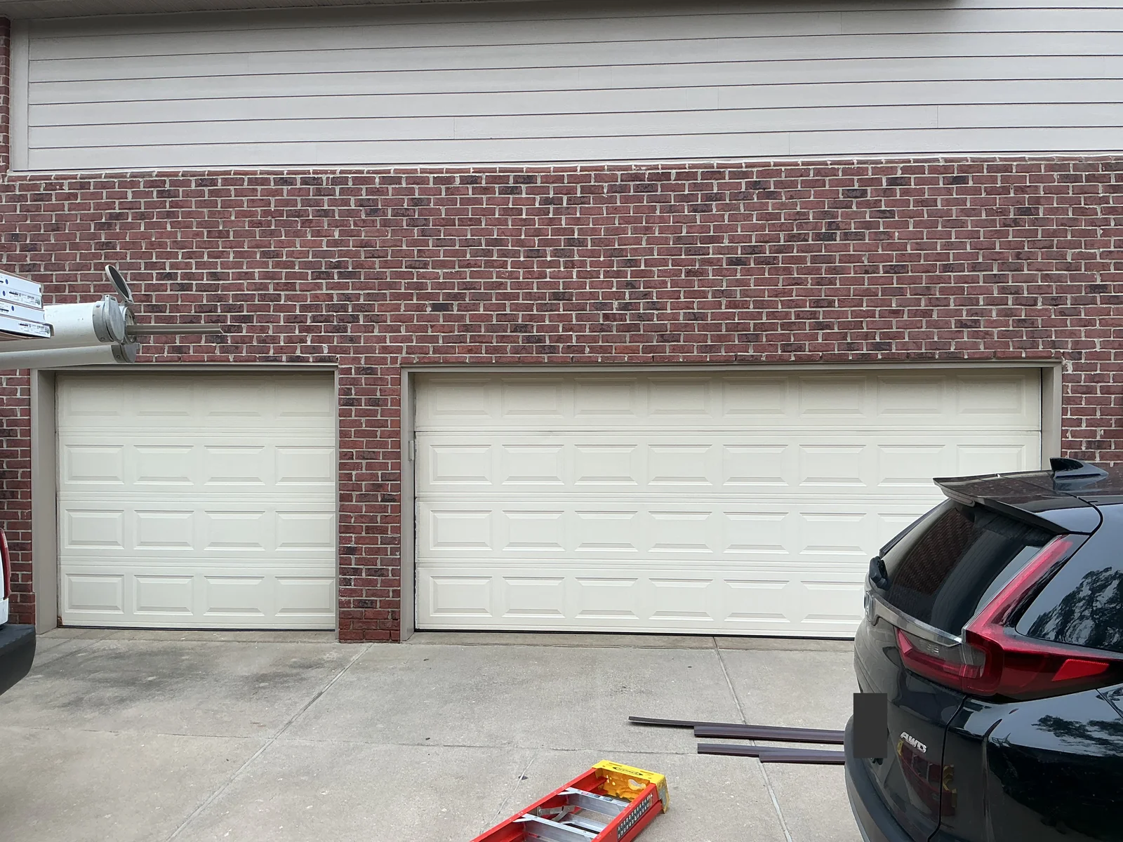 Original light colored single and double garage doors with smaller rectangular panels.